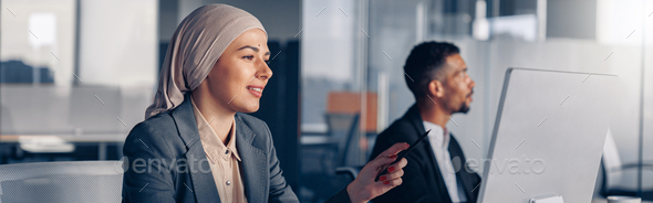 Smiling muslim businesswoman in hijab working on computer while sitting in modern office - Stock Photo - Images
