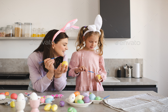 Smiling woman making Easter decorations with kid girl together - Stock Photo - Images