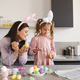Smiling woman making Easter decorations with kid girl together - PhotoDune Item for Sale