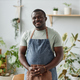 Smiling black man as gardener wearing apron posing indoors looking at camera - PhotoDune Item for Sale