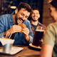 Happy man eating burger while gathering with friends in a bar. - PhotoDune Item for Sale