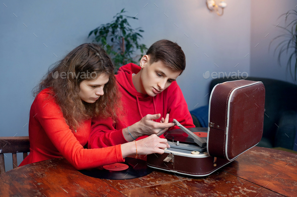 Young couple, man and woman, are interested in studying an old vinyl record player