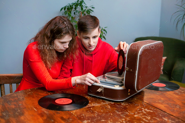 Young couple, man and woman, are interested in studying an old vinyl record player