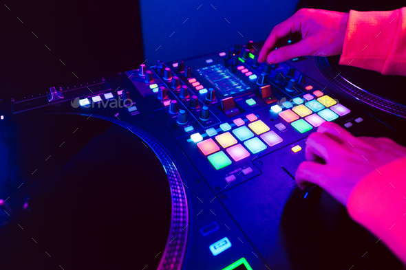 Hands of a DJ creating and regulating music on dj console mixer at club concert - Stock Photo - Images