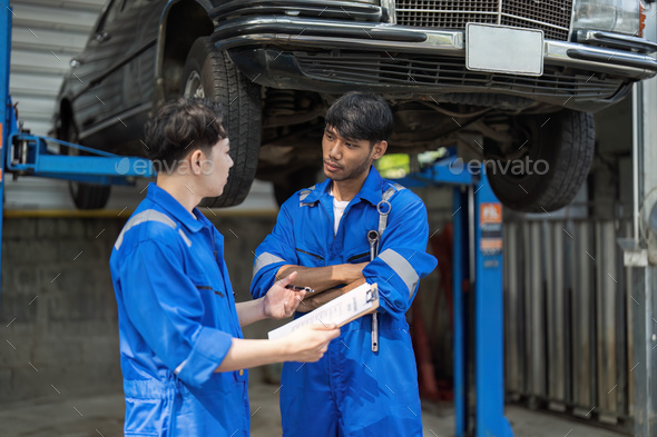 Two Mechanics in a Service are Inspecting a Car After They Got the Diagnostics Results. Female - Stock Photo - Images