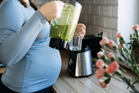 Green Smoothies Recipes For Pregnancy and Postpartum, Prenatal Nutrition. Pregnant woman preparing - Stock Photo - Images