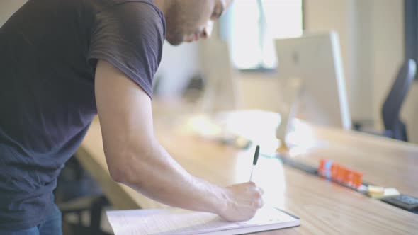 Young man writing notes in office