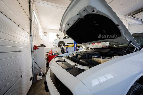 Muscle car with open hood at service repair station in lift. - Stock Photo - Images