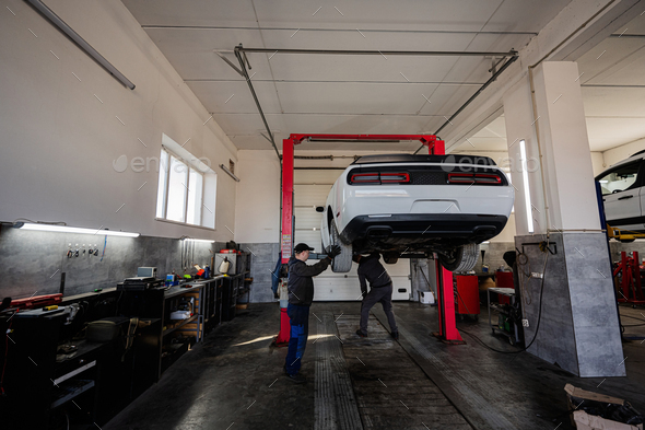 Two mechanic in service repair station working with muscle car in lift. - Stock Photo - Images