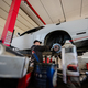 Mechanic in service repair station working with muscle car, dismantles a wheel on lift. - PhotoDune Item for Sale