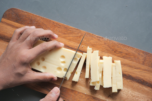 cutting cheese with knife on a chipping board  - Stock Photo - Images