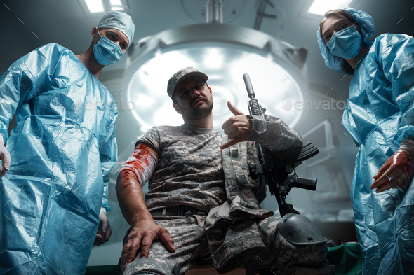 Two doctors and injured soldier looking at camera together - Stock Photo - Images