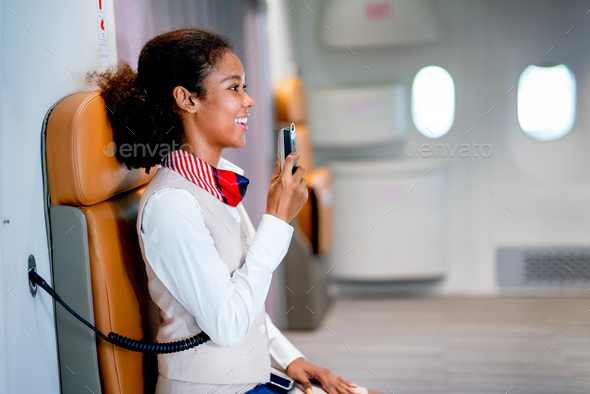 Air hostess or airline staff sit on cabin crew seat and use microphone of airplane to give