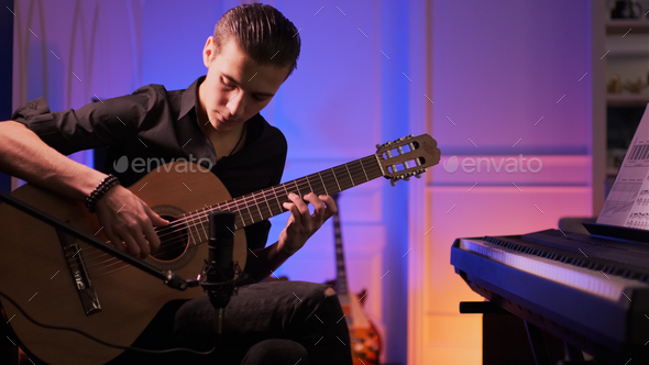 Man plays guitar. Young man plays a musical instrument. Musician records his composition - Stock Photo - Images