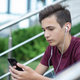 Teenage boy is using mobile phone, outdoors. Handsome young man with smartphone and earphones.  - PhotoDune Item for Sale
