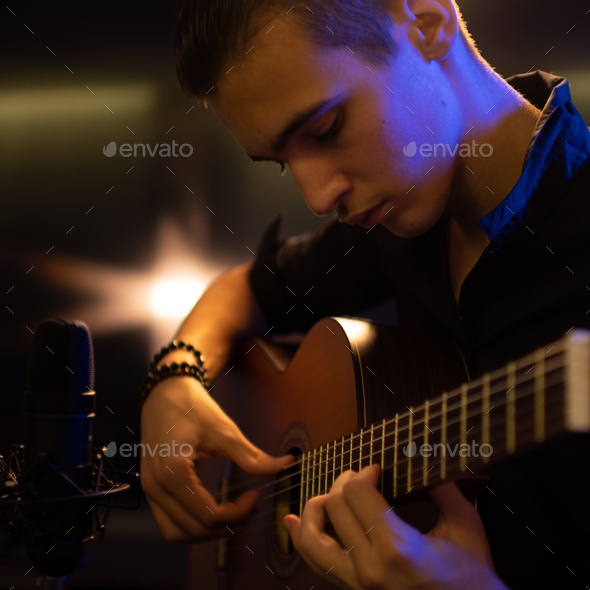 Man with a classical guitar in a neon glow. Teenager plays guitar. Young man plays a music - Stock Photo - Images