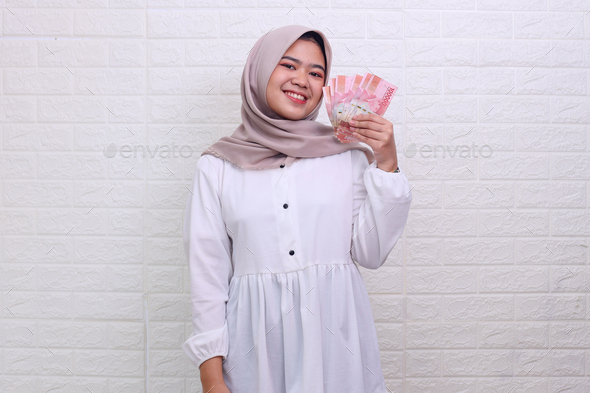 Muslim woman smiling while holds some money - Stock Photo - Images