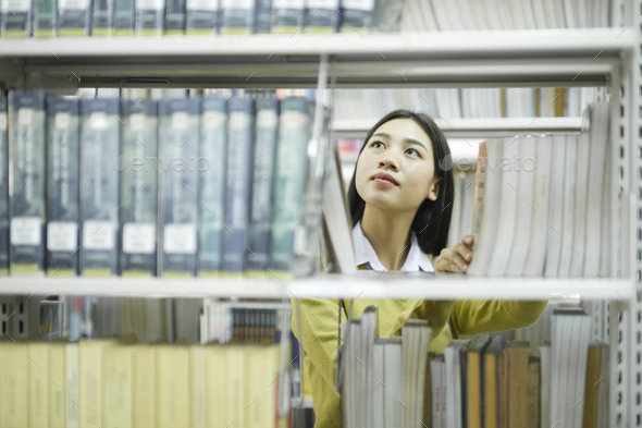 Student choosing and reading book at library. - Stock Photo - Images