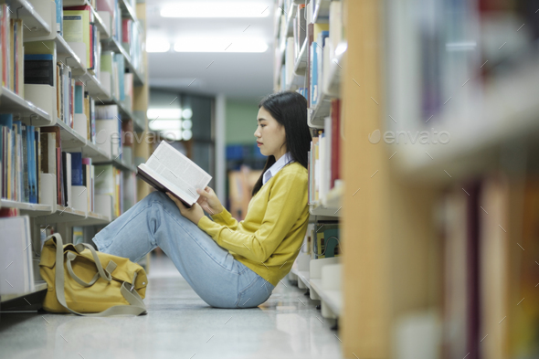 Student sitting on the floor and reading at library. - Stock Photo - Images