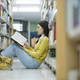 Student sitting on the floor and reading at library. - PhotoDune Item for Sale