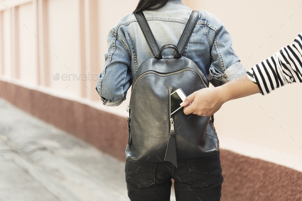 Thief stealing mobile from traveller bag on street. - Stock Photo - Images