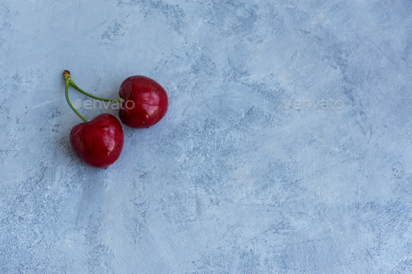 Two cherries on a gray background. - Stock Photo - Images