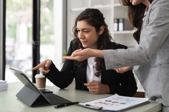 Two smart multiethnic business people working together with laptop while working on project in - Stock Photo - Images