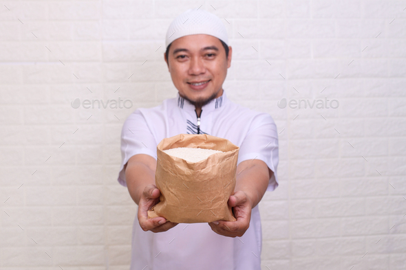 Asian Muslim man hand giving alms bag of rice. Zakah fitrah concept. - Stock Photo - Images