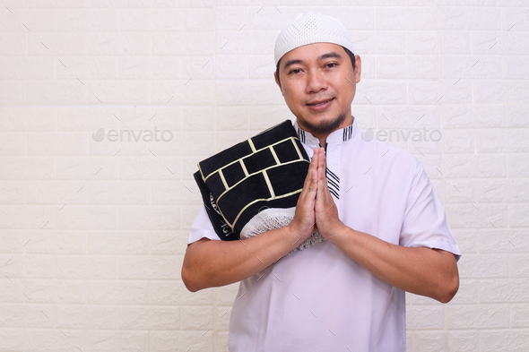 Smiling Asian Muslim man gesturing Eid Mubarak greeting  - Stock Photo - Images