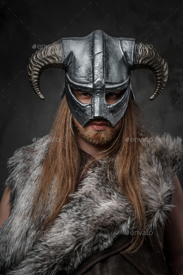 Headshot of savage viking dressed in fur and horned helmet - Stock Photo - Images