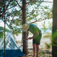 caucasian man wearing a hat putting up a tent. Family camping concept - PhotoDune Item for Sale