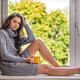 long haired brunette sitting on the windowsill and drinking morning tea - PhotoDune Item for Sale
