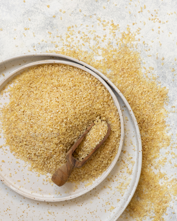 Pile of Dry uncooked bulgur wheat grain with a scoop on a plate top view. Healthy food - Stock Photo - Images