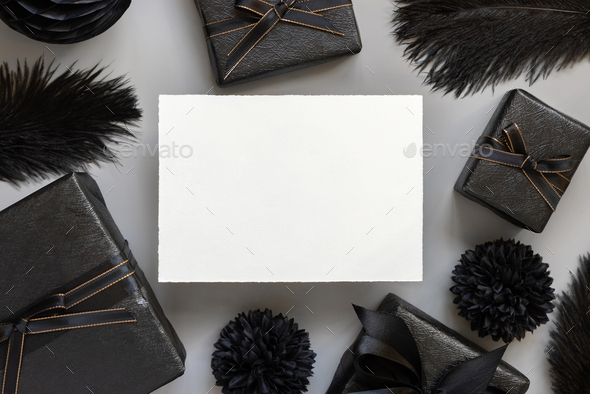 Blank card between Wrapped Gift Boxes, black paper flowers and feathers, mockup - Stock Photo - Images