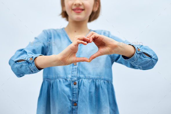 Smiling little girl make heart sign with hands - Stock Photo - Images