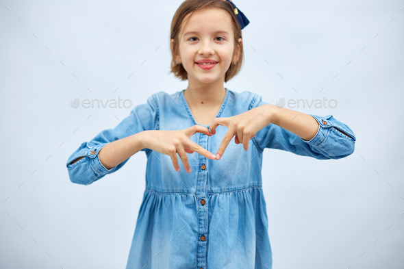 Smiling little girl make heart sign with hands - Stock Photo - Images