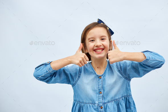 Smiling teen girl child in jeans dress make thumb up - Stock Photo - Images