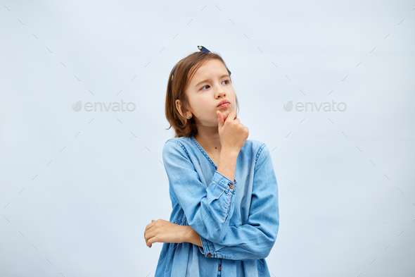 Thoughtful teen girl child wearing jeans dress with finger thinking - Stock Photo - Images