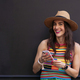 Smiling woman in hat and colorful t-shirt using smart phone. - PhotoDune Item for Sale