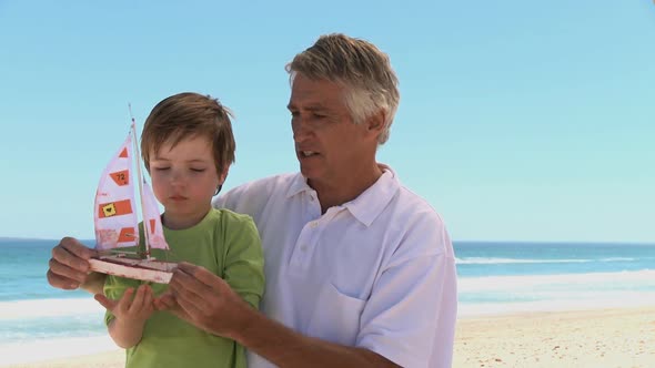 MS Tracking Left OF A GRANDFATHER AND GRANDSON PLAYING WITH A TOY BOAT