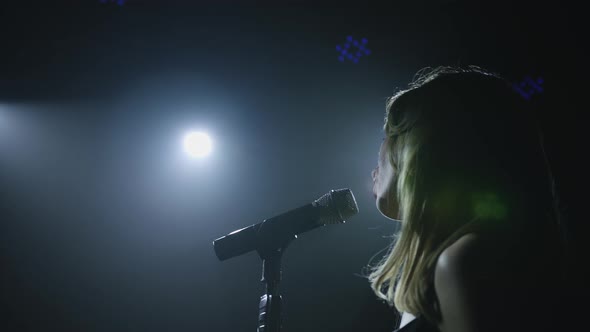 Close-up of the Face of the Singer with Microphone on a Black Smoky Background. The Singer Sings a alt
