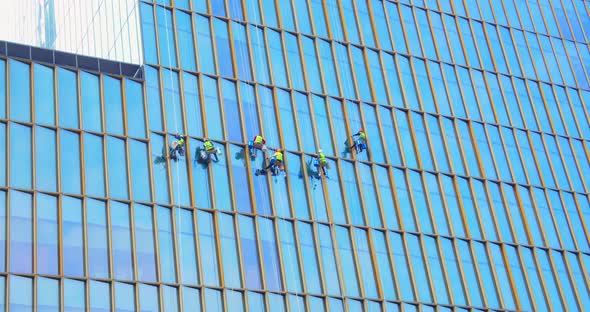Six Men Workers in Red and Yellow Work Clothes Cleaning the Exterior Windows of a Business alt