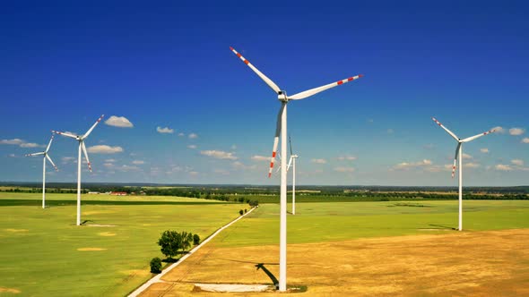 Aerial view of white wind turbine on green field alt