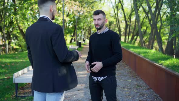 Portrait of Handsome Bearded Young Man Talking with Friend Standing in City Park on Summer Spring alt