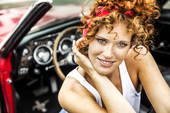 Portrait of smiling redheaded woman in sports car