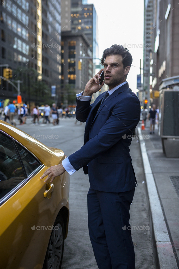 Businessman on the phone entering ywllow taxi in Manhattan