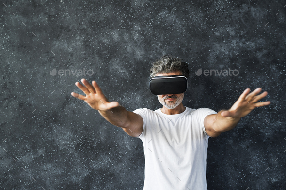 Mature man wearing VR glasses reaching out with hands