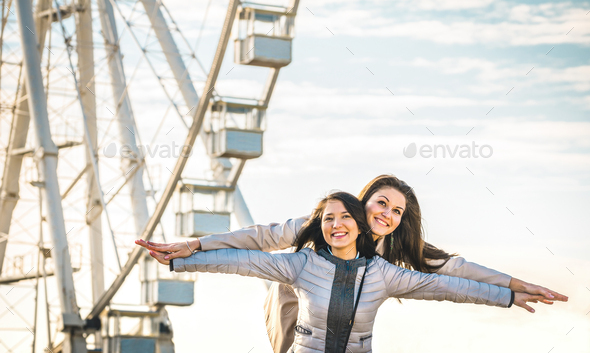 Young women best friends enjoying time together outdoors at ferris wheel - Stock Photo - Images
