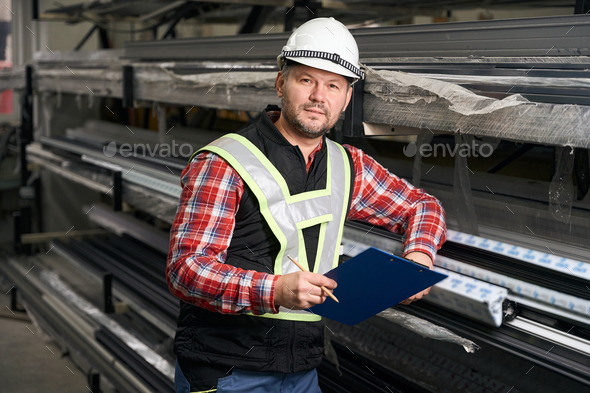 Portrait of man holding clipboard, looking at the camera - Stock Photo - Images