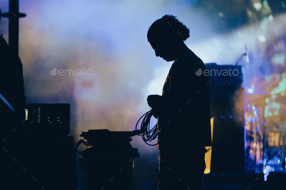 Silhouette of a stage worker standing on a stage with cables